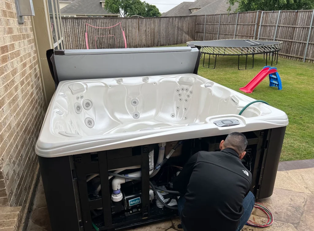 Technician inspecting outdoor hot tub electrical components, illustrating why you should hire an electrician.